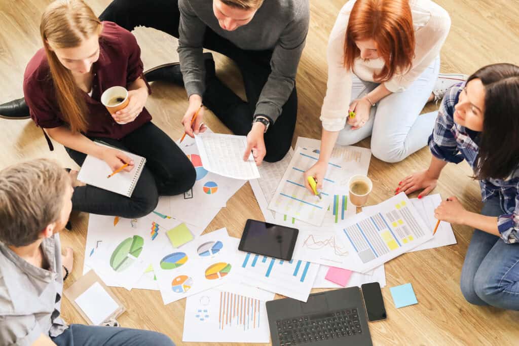 People sit in a circle discussing with sheets of paper in front of them.