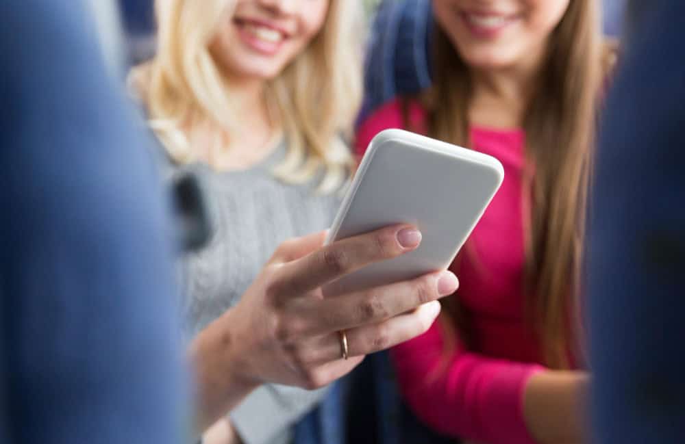 A woman shows something on her phone to a friend.