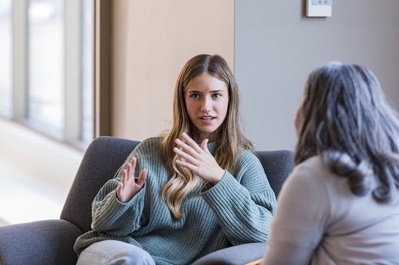 A young professional woman participating in a one-on-one coaching session with a colleague, discussing career development and personal growth in a relaxed office setting.