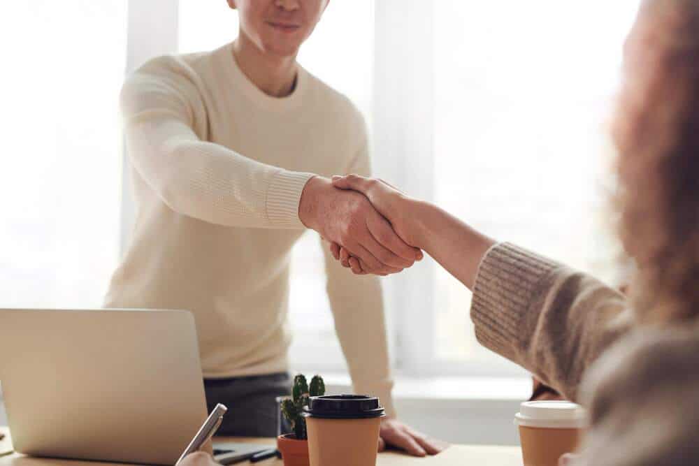 Man and woman shaking hands over table.