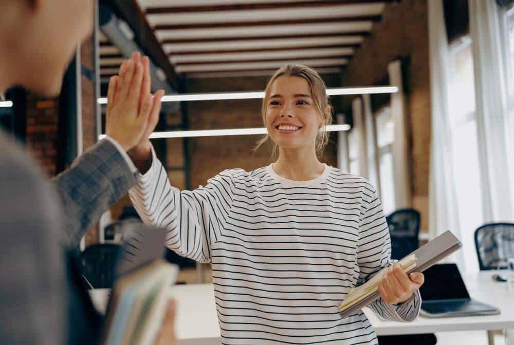 Smiling woman giving high five to co-worker.