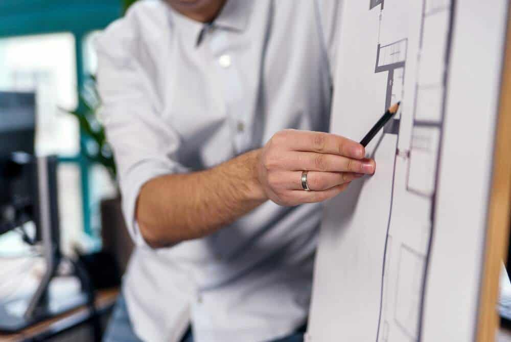 Man points on a drawing on a board with a pencil.