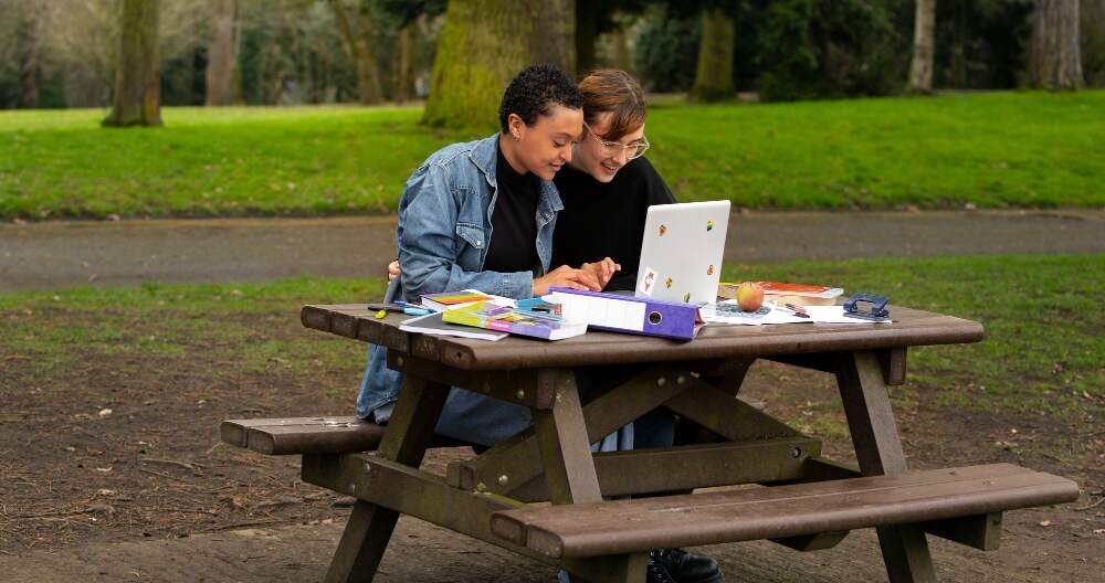 Young people sitting on an outdoor table while studying