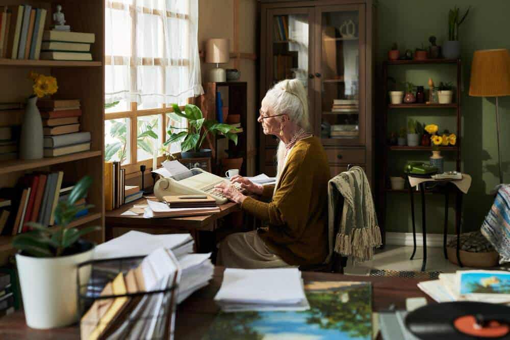 An elderly lady sitting in her office typing on an old typewriter