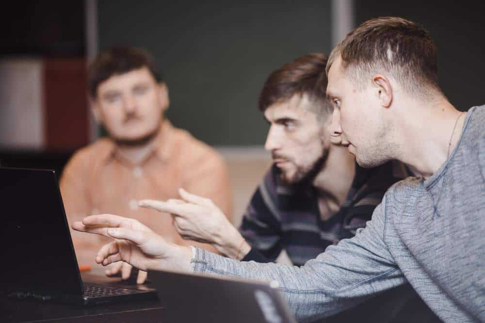 Three people sitting together discussing something they have on a laptop screen