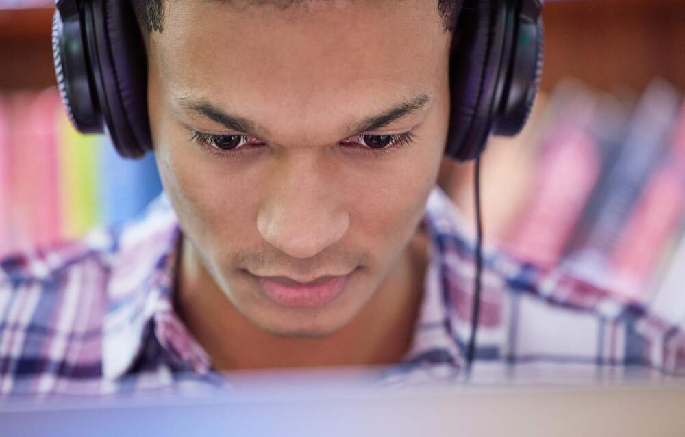 Close-up of a learner who with headphones focusing on something on his computer screen